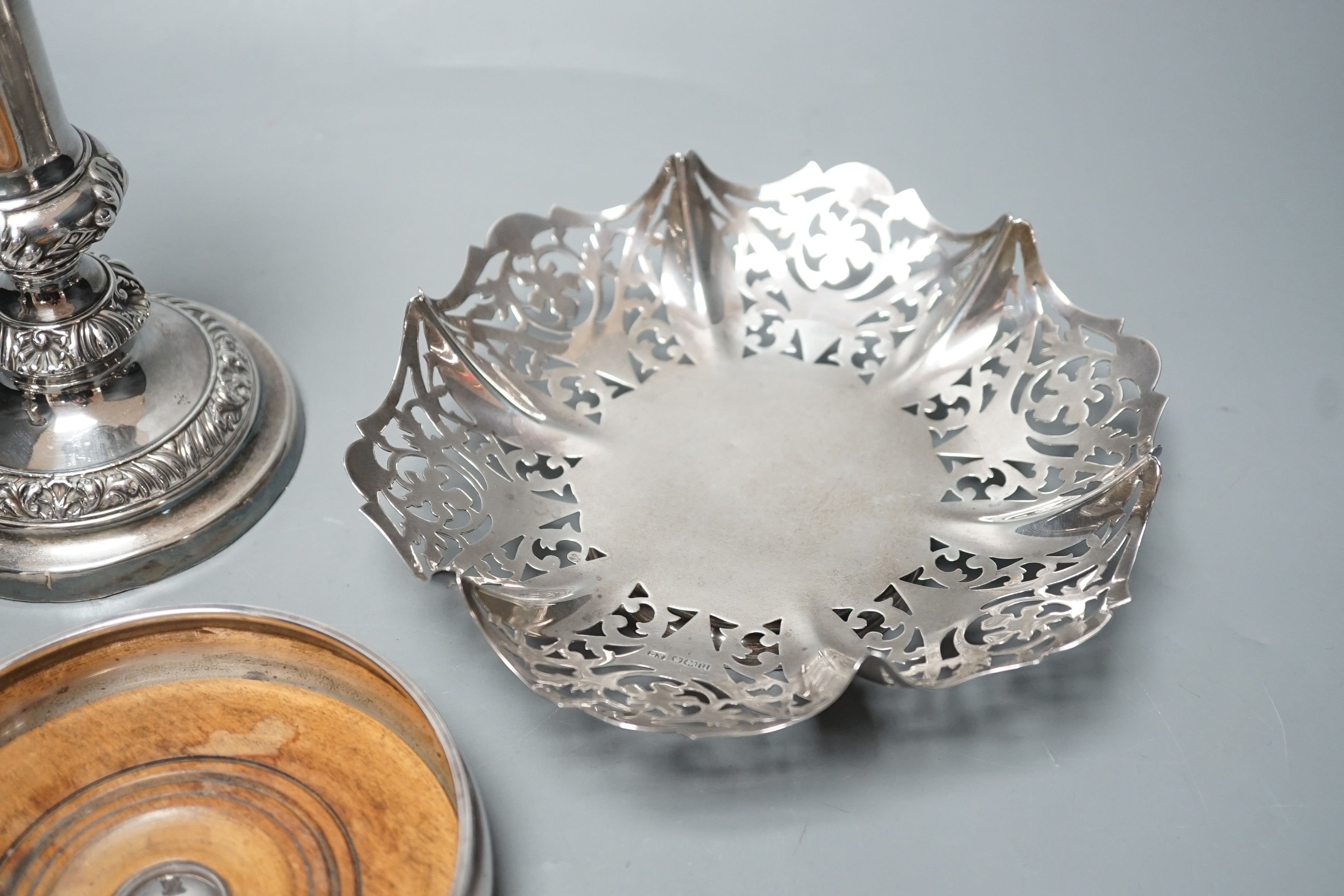A modern silver mounted wine coaster, London, 1996, diameter 12.4cm, an earlier pierced silver bonbon dish and a pair of plated candlesticks.